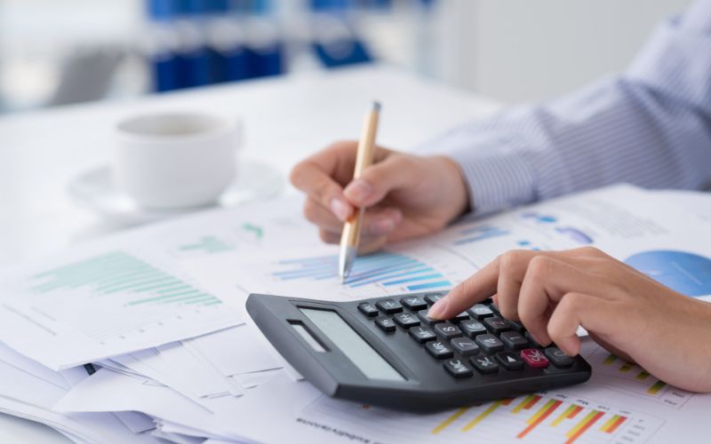 A person in CA using a calculator to calculate numbers on a paper.