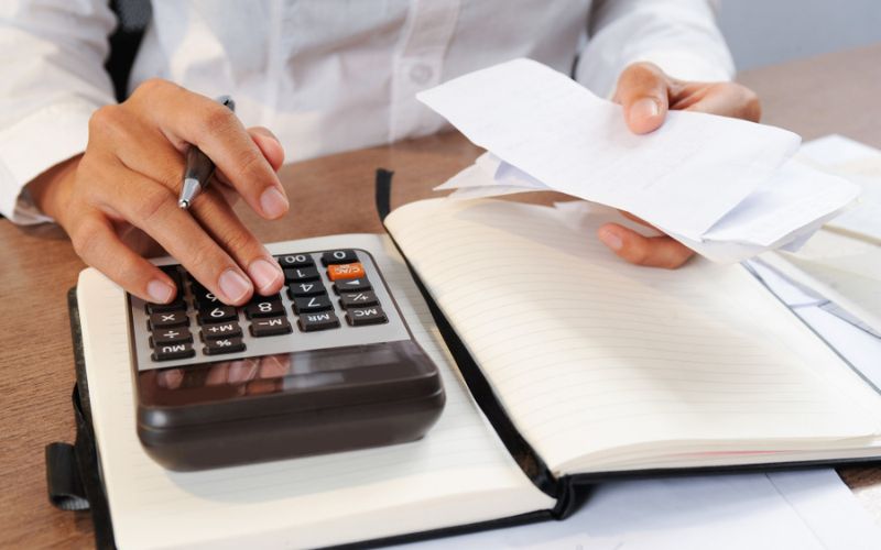 A businesswoman using a calculator to calculate tax using Tally ERP 9 software